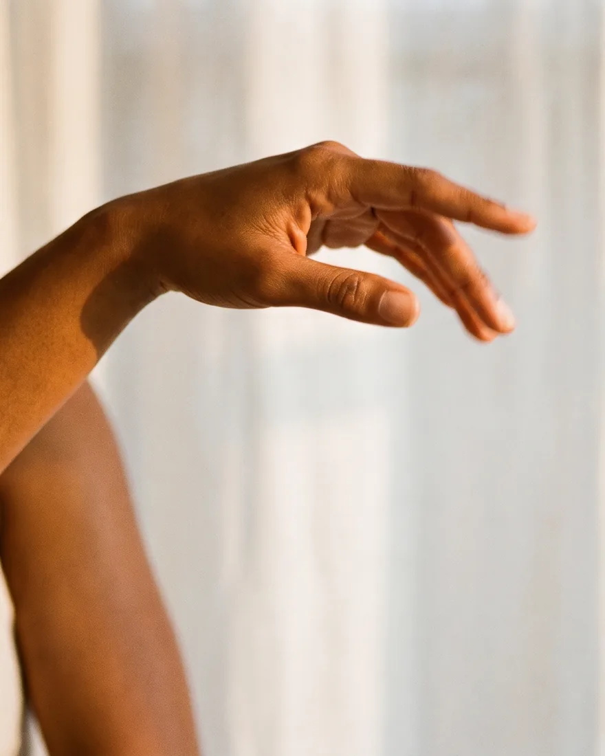 A hand extended in a soft, open gesture, in warm natural light